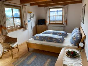 ein Schlafzimmer mit einem Bett, einem Tisch und zwei Fenstern in der Unterkunft Apartment Landhaus Bachwinkl in Reit im Winkl