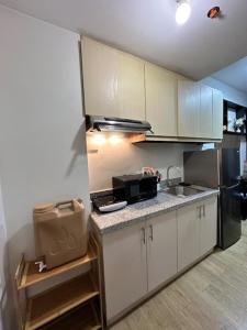 a kitchen with white cabinets and a sink and a microwave at Matty’s homestay in Manila