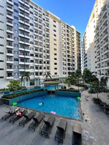 a large swimming pool with chairs and large buildings at Matty’s homestay in Manila