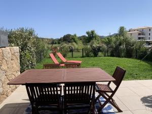 een houten tafel en stoelen op een terras bij Eluard 04 - Domaine d'Arca - PORTO-VECCHIO - Rez de jardin - 4 à 6 pers in Porto-Vecchio