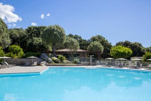 une grande piscine bleue avec des chaises et des parasols dans l'établissement Eluard 04 - Domaine d'Arca - PORTO-VECCHIO - Rez de jardin - 4 à 6 pers, à Porto-Vecchio