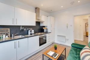 kuchnia i salon z białymi szafkami i zieloną kanapą w obiekcie 2 Bedroom Apartment Near City Centre, Uni & Parks! w Cardiff