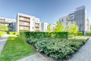 a hedge in front of a building with buildings at Dom & House - Apartamenty Nadmorski Dwór in Gdańsk