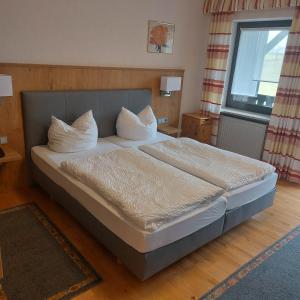 Schlafzimmer mit einem Bett mit weißer Bettwäsche und Kissen in der Unterkunft Gasthof Pension Grüne Au 