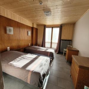 two beds in a room with wooden walls at Hotel du lac des Corbeaux in La Bresse