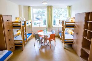 a room with a table and chairs and bunk beds at Jugendherberge Friedrichstadt in Friedrichstadt