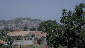 een uitzicht op een stad met een heuvel op de achtergrond bij CommonLens Inn in Entebbe
