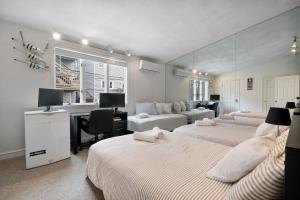a hotel room with three beds and a desk and a desk at Heart of Southie - Hot Tub + Walk to Top Bars in Boston