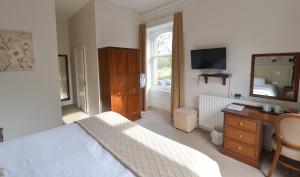 a bedroom with a bed and a dresser and a mirror at Steeton Hall Hotel & Restaurant in Steeton