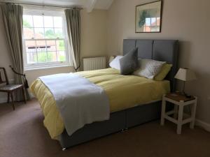 a bedroom with a bed with a yellow blanket and a window at Close House Cottage in York
