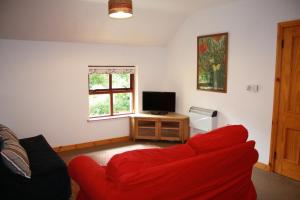 a living room with a red couch and a television at Ballylagan Organic Farm in Straid