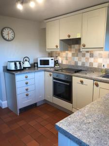 a kitchen with white cabinets and a clock on the wall at Close House Cottage in York
