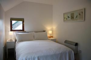 1 dormitorio con 1 cama blanca y 2 lámparas en Ballylagan Organic Farm, en Straid