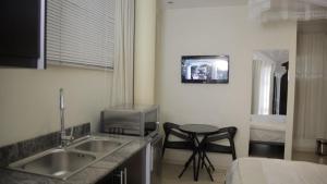 een keuken met een wastafel en een tv aan de muur bij CommonLens Inn in Entebbe