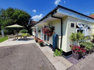 Cette petite maison dispose d'une table et d'une terrasse. dans l'établissement The Nook located in a beautiful garden setting with parking, à Stratford-upon-Avon