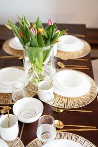 una mesa con platos blancos y un jarrón de flores en 130m2 Loft - Dachterrasse, Netflix, Badewanne, Kaffee, en Rosenheim