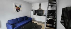 uma sala de estar com um sofá azul e uma cozinha em Duplex dans pavillon neuilly sur marne entre Paris et disney em Neuilly-sur-Marne