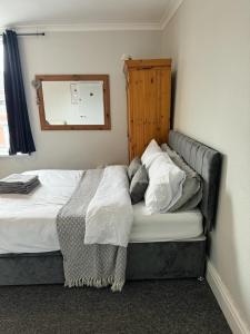 a bedroom with a bed with white sheets and a mirror at P&S rooms guesthouse Lincoln city centre in Lincolnshire