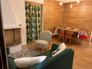 Casetta nel bosco - Appartamento "Le betulle" Lavarone في Chiesa: غرفة معيشة مع طاولة وأريكة خضراء