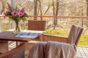 a table and chairs with a vase of flowers on a porch at Birdie mit Ostseeblick Haus Fore in Lohme