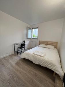 a white bedroom with a bed and a desk at Appartement Dammarie-les-Lys in Dammarie-lès-Lys