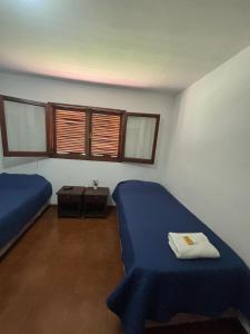 a bedroom with two beds and a table and windows at HOSTAL TILIAN in Salta