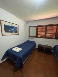 a bedroom with a bed with a blue blanket and windows at HOSTAL TILIAN in Salta