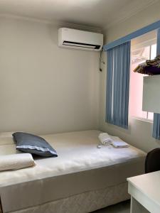 Cama en habitación con ventana y ventilador en Pousada Rara House, en Jaraguá do Sul