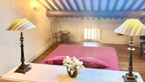 a bedroom with a pink bed and two lamps on a table at Domaine Les Terres de Saint-Hilaire in Ollières