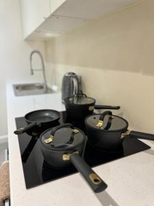 een groep van vier potten op een fornuis in een keuken bij Modern 1BD Flat in Londen