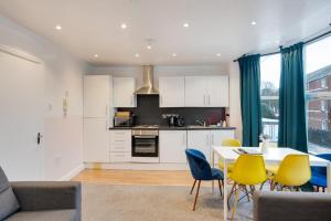 a kitchen and dining room with a table and yellow chairs at Duplex Apartment For Up to 13 Near City Centre in Cardiff