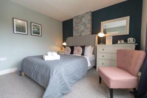 1 dormitorio con cama, silla y espejo en Wyndgrove House, en Seahouses