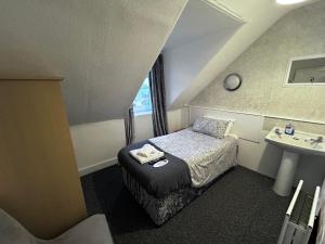 a small bedroom with a bed and a sink at Dunarle Guesthouse in Oban