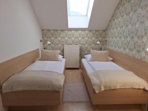 2 letti in una piccola camera con finestra di Apartments Mertelj a Kranjska Gora