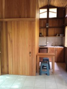 a kitchen with wooden walls and a table and two stools at Cabañas Bajo Bosque Drake in Drake