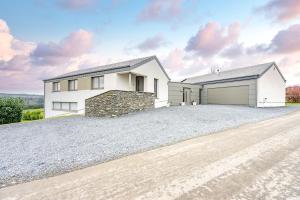 a white house with a garage on a gravel driveway at Villa Aquatenne in Tenneville