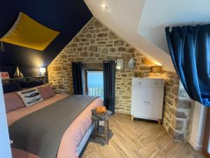 a bedroom with a large bed and a stone wall at Gîtes d'Izel n°2 in Ploemel