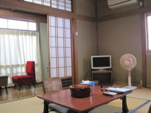 sala de estar con mesa y TV en Suminoe Ryokan en Onomichi