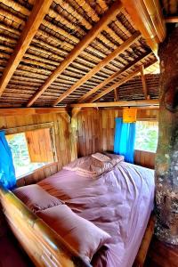 a bed in a room with a wooden ceiling at Lumbung Langit Bali house & hostel in Tampaksiring