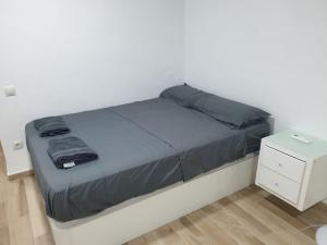 een bed met een grijze deken en een nachtkastje bij Acogedor Apartamento 38 verdi7 in Torremolinos