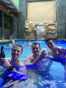 Tres hombres en una piscina bebiendo cerveza en Poshtel Arenal en Fortuna