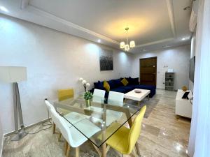 ein Wohnzimmer mit einem Glastisch und gelben Stühlen in der Unterkunft Appartement Tanger Moulay Ismail in Tangier