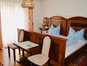 Schlafzimmer mit einem Holzbett mit einem Tisch und Stühlen in der Unterkunft Frühstückspension Kirchenwirt in Obervellach