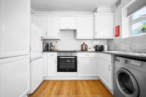 a white kitchen with white cabinets and a dishwasher at Stunning Two Bedroom House - Parking & Garden - Near Birmingham City Centre - 55H in Birmingham