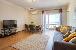 uma sala de estar com um sofá e uma mesa com uma televisão em Ericeira Beach Apartment na Ericeira