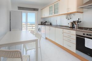 a kitchen with white cabinets and a table with chairs at Ericeira Beach Apartment in Ericeira