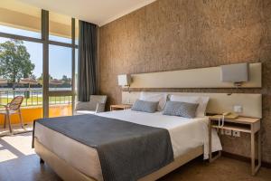 a bedroom with a large bed and a balcony at VILA PARK Nature & Business Hotel in Santo André