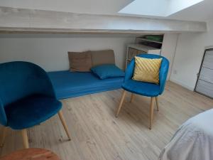 ein kleines Zimmer mit einem blauen Sofa und zwei Stühlen in der Unterkunft Ty'Château Carignan de Bordeaux B&B in Carignan