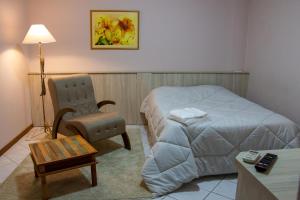 Habitación de hotel con cama y silla en Hotel Villa Souza Ltda en Santa Cruz do Sul