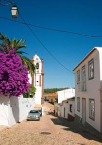 a street with a building with a clock tower and purple flowers at Stylish town house in Silves in Silves